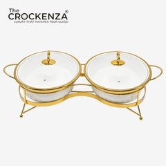 A double-tier gold-plated serving stand with two white glass bowls and matching lids, shown on a light gray background with The Crockenza logo in the top left corner.