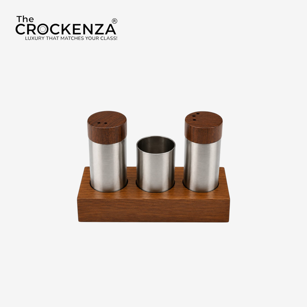A three-compartment wooden and stainless steel spice/tea accessory set on a marble countertop in a kitchen setting. The set includes two cylindrical containers with dark wood lids and a center cup holding wooden toothpicks, all resting on a matching rectangular wooden base.